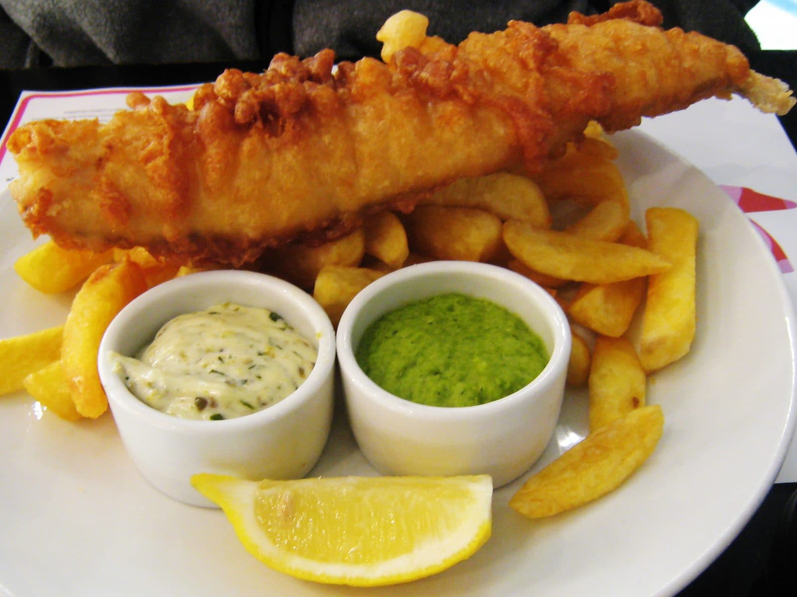 Golden fish fillet with chunky chips, mushy peas, tartare sauce and a lemon wedge