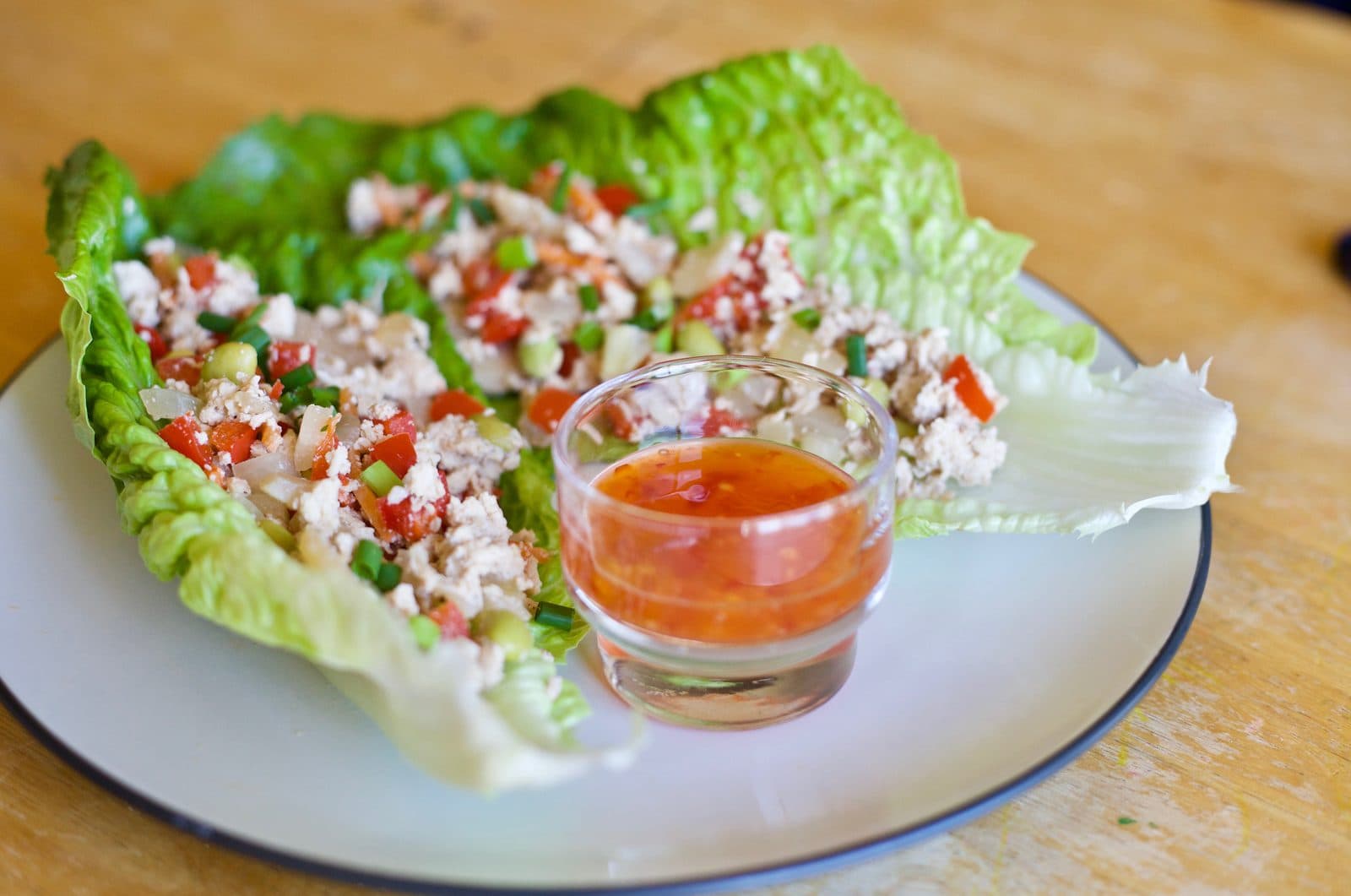Minced chicken with diced red pepper and spring onion in romaine lettuce leaves, with a small dish of chilli dipping sauce
