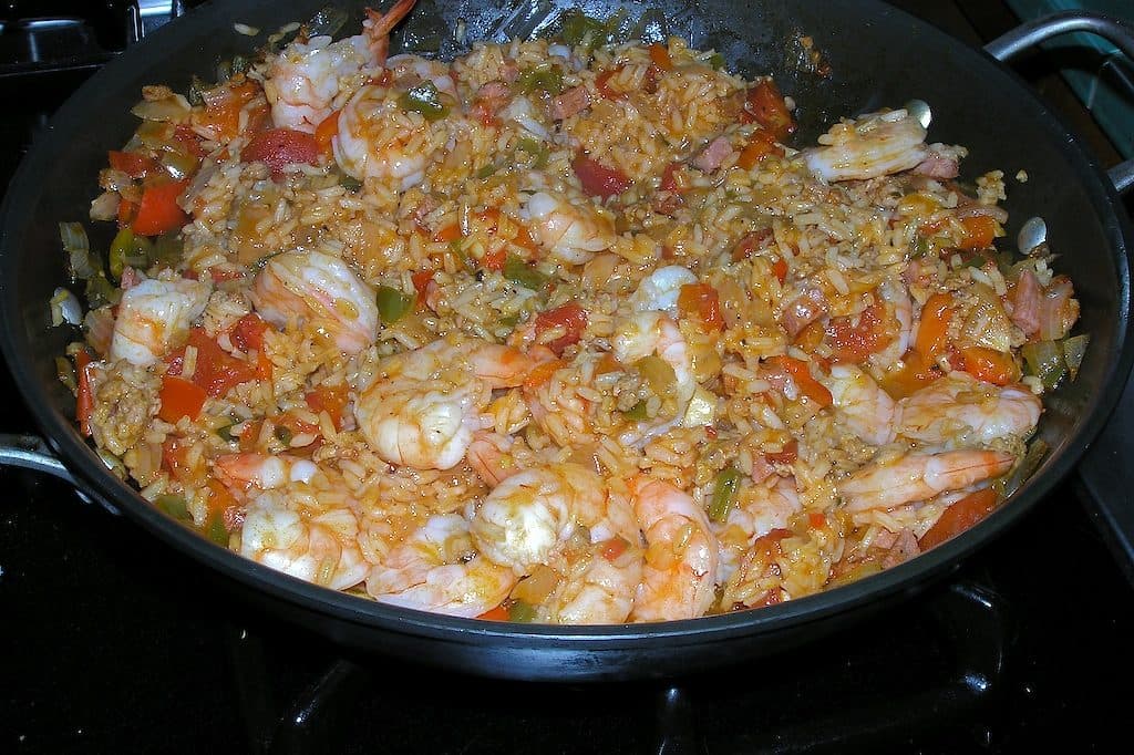 Skillet of jambalaya-style rice with prawns, tomato and peppers on the stove