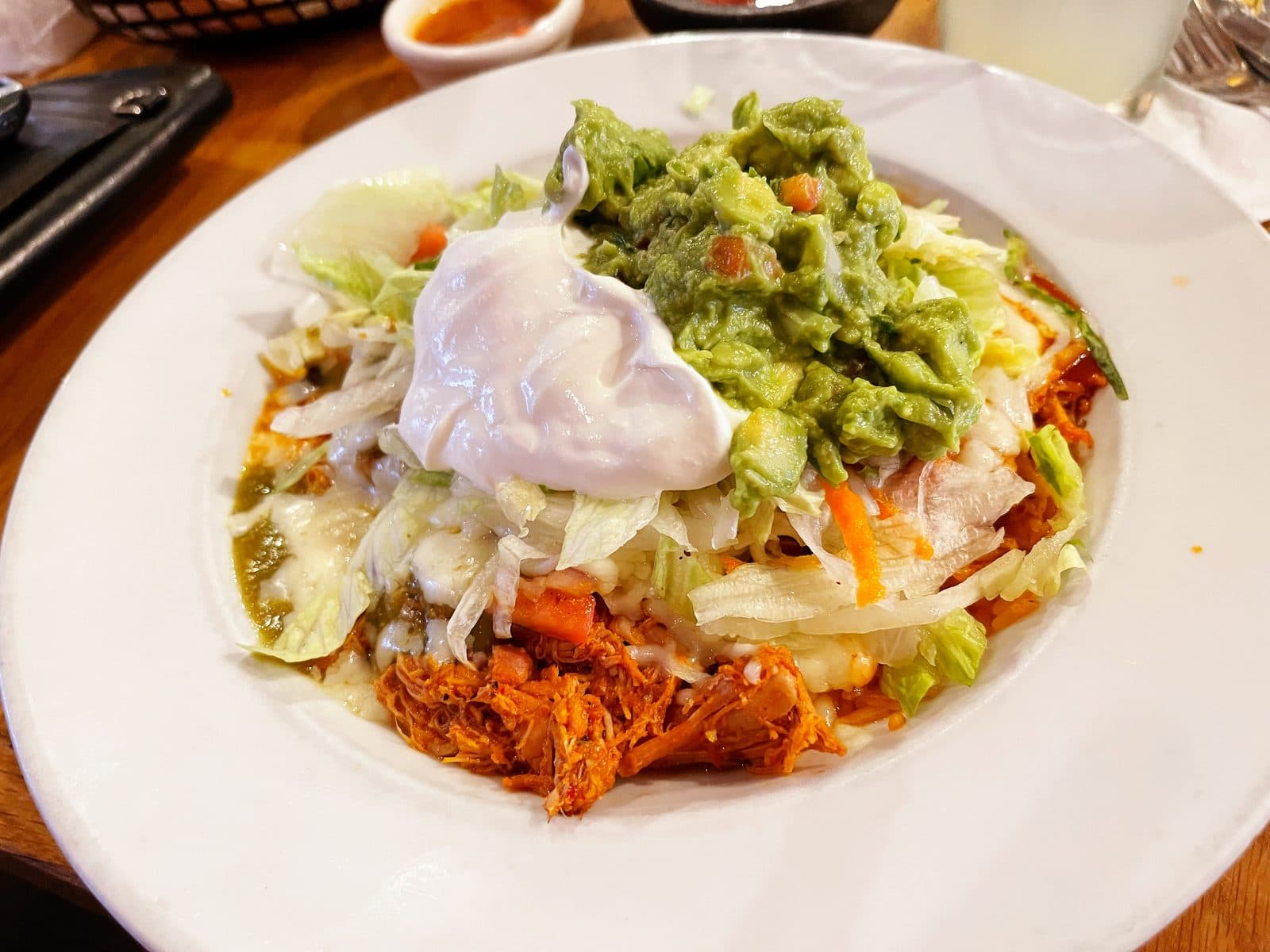 Shredded chicken burrito bowl topped with lettuce, guacamole and sour cream