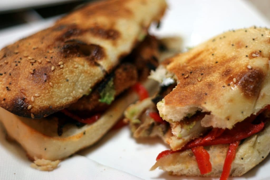 Toasted chicken panini with roasted red peppers, cut in half
