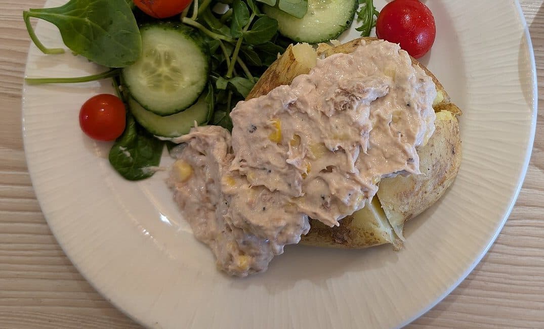 Jacket potato topped with tuna and sweetcorn, with salad leaves, cucumber and cherry tomatoes