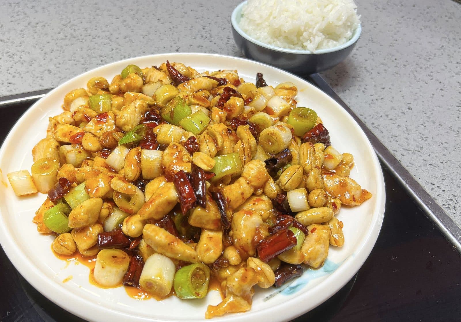Kung pao chicken with peanuts, dried chillies and scallion pieces, with a bowl of rice (cropped)