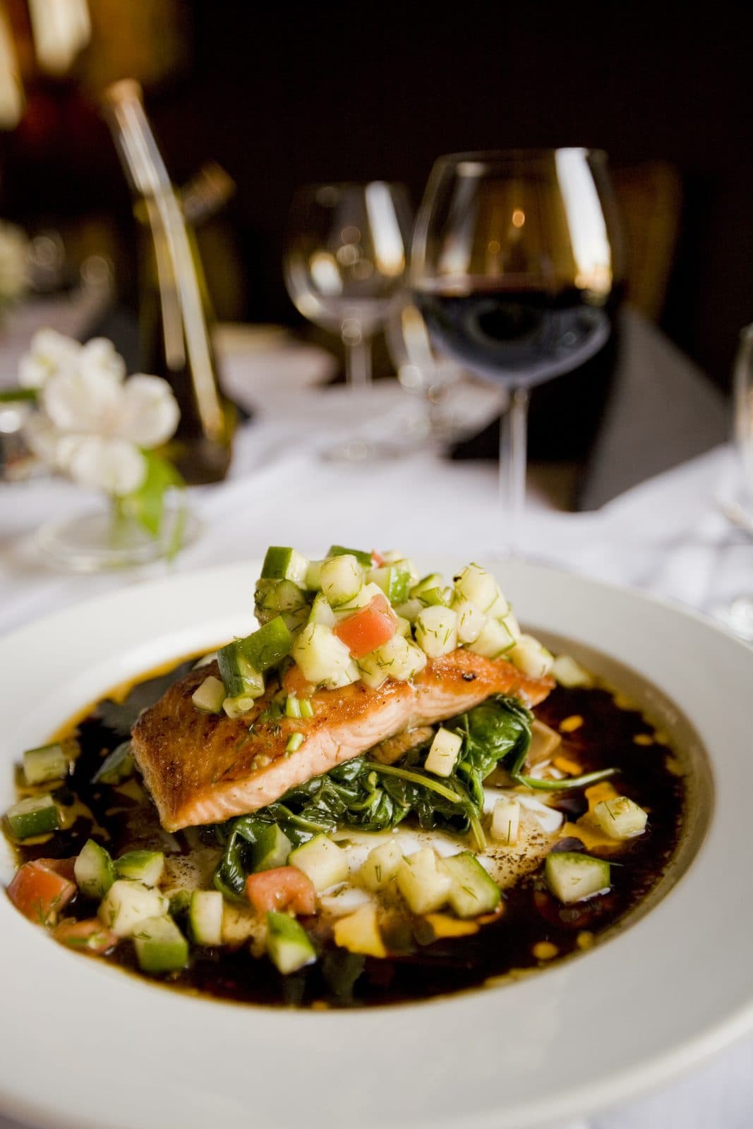 Seared salmon fillet on greens topped with diced cucumber, zucchini and dill
