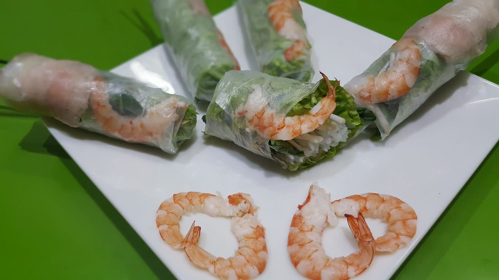 Vietnamese rice-paper summer rolls filled with prawns, lettuce and vermicelli, with whole prawns on the plate