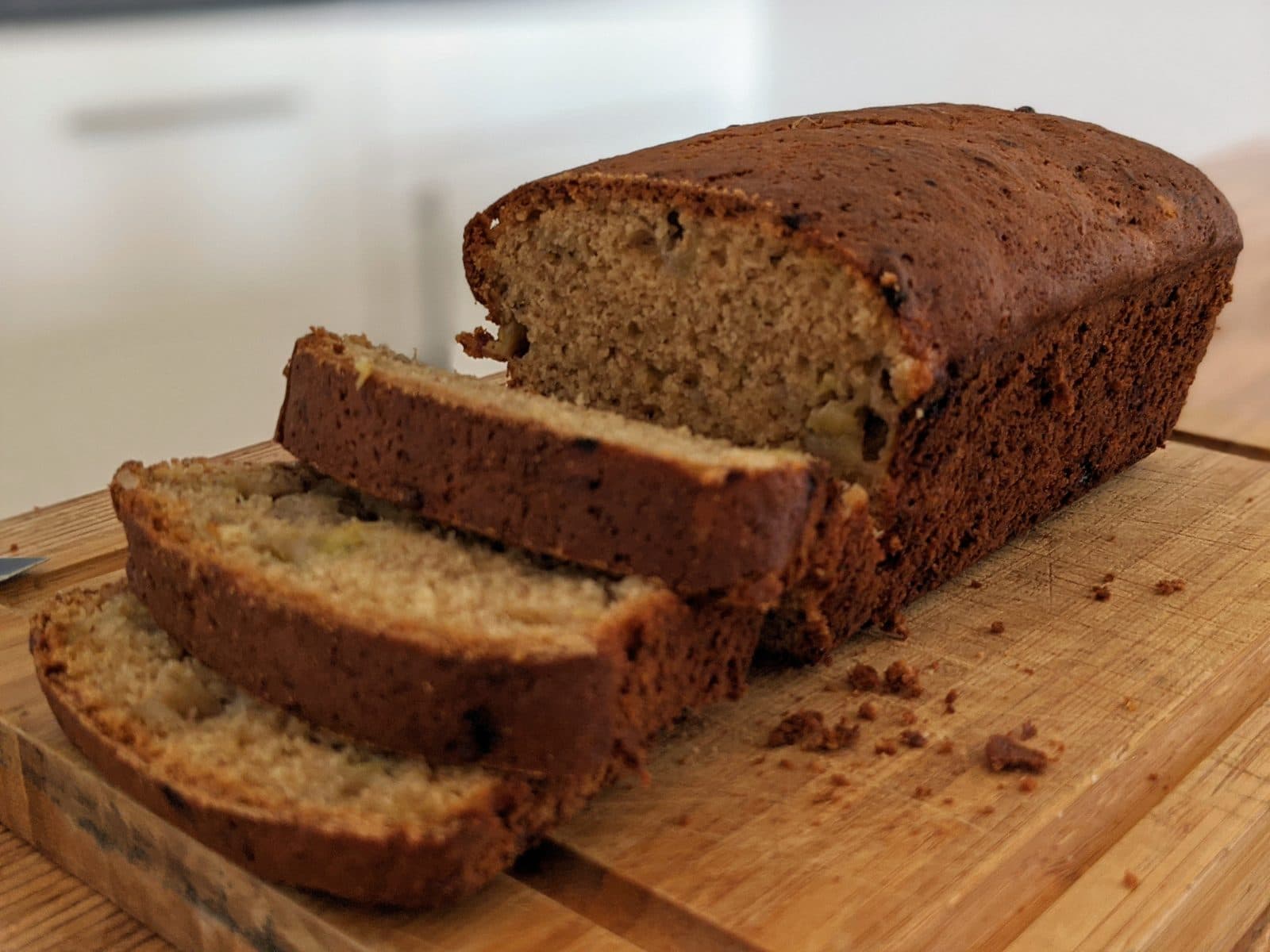 Banana bread loaf with three slices cut on a wooden board