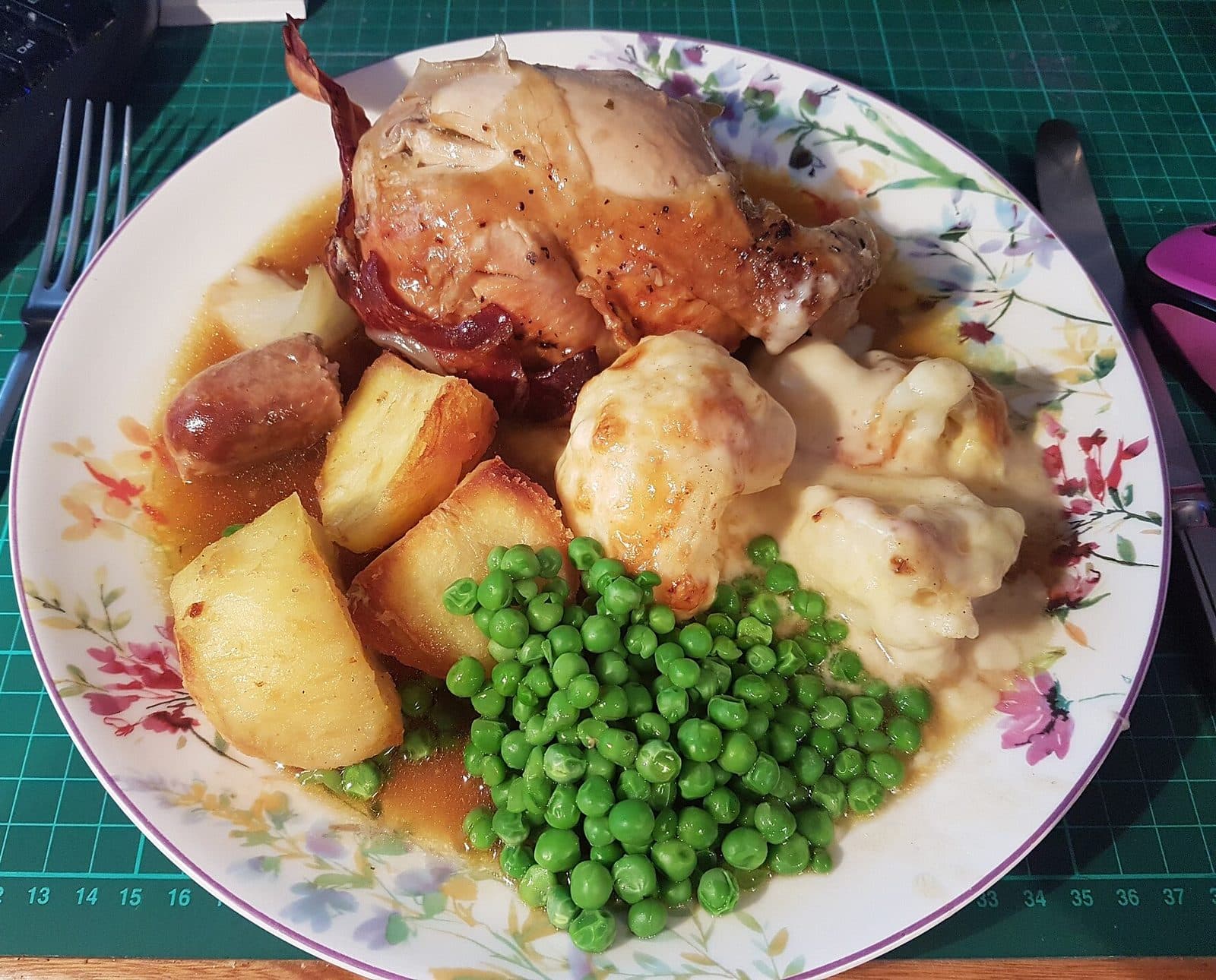 Roast chicken dinner with roast potatoes, peas, cauliflower cheese and gravy
