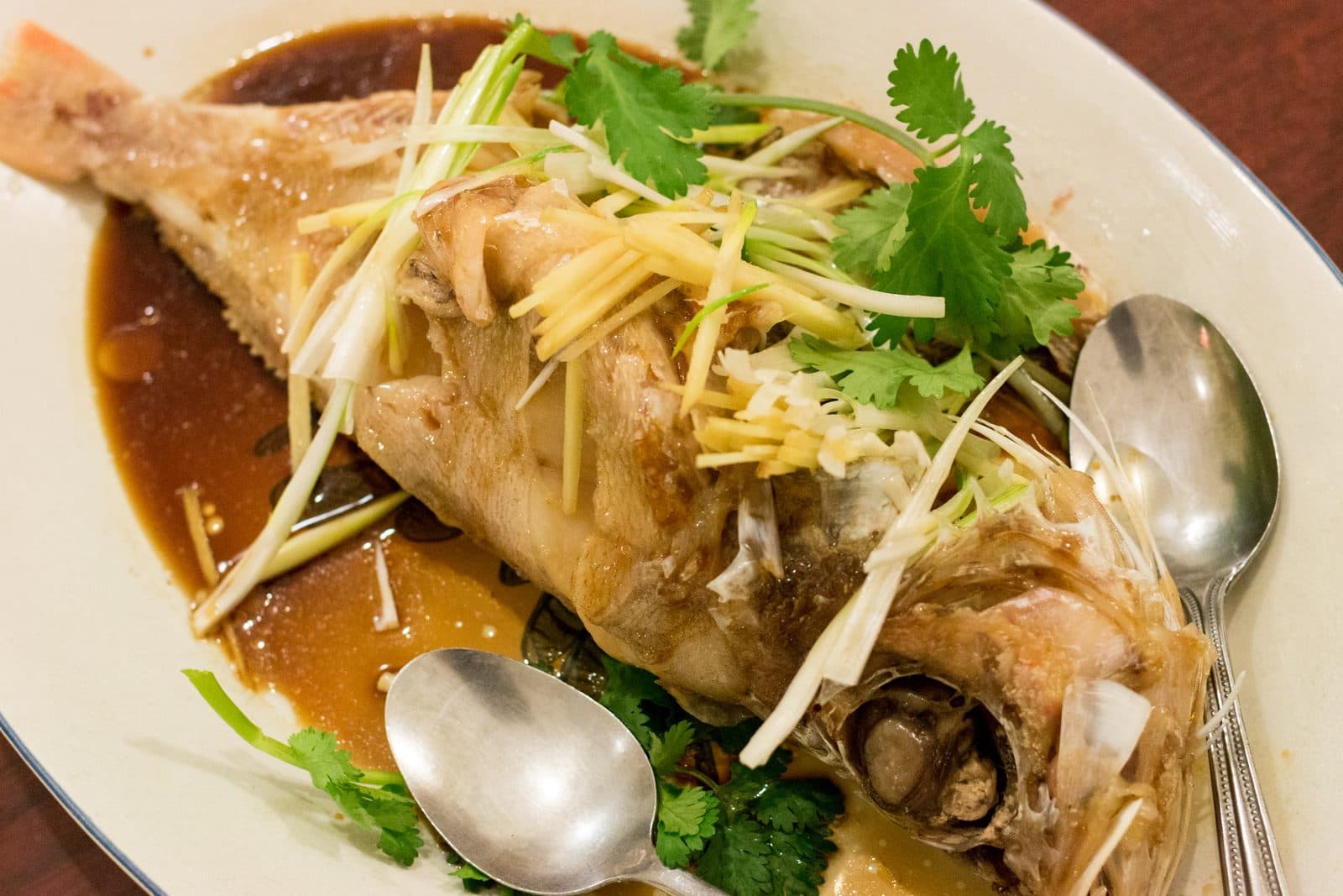 Whole steamed fish topped with shredded ginger, scallions and coriander in soy sauce