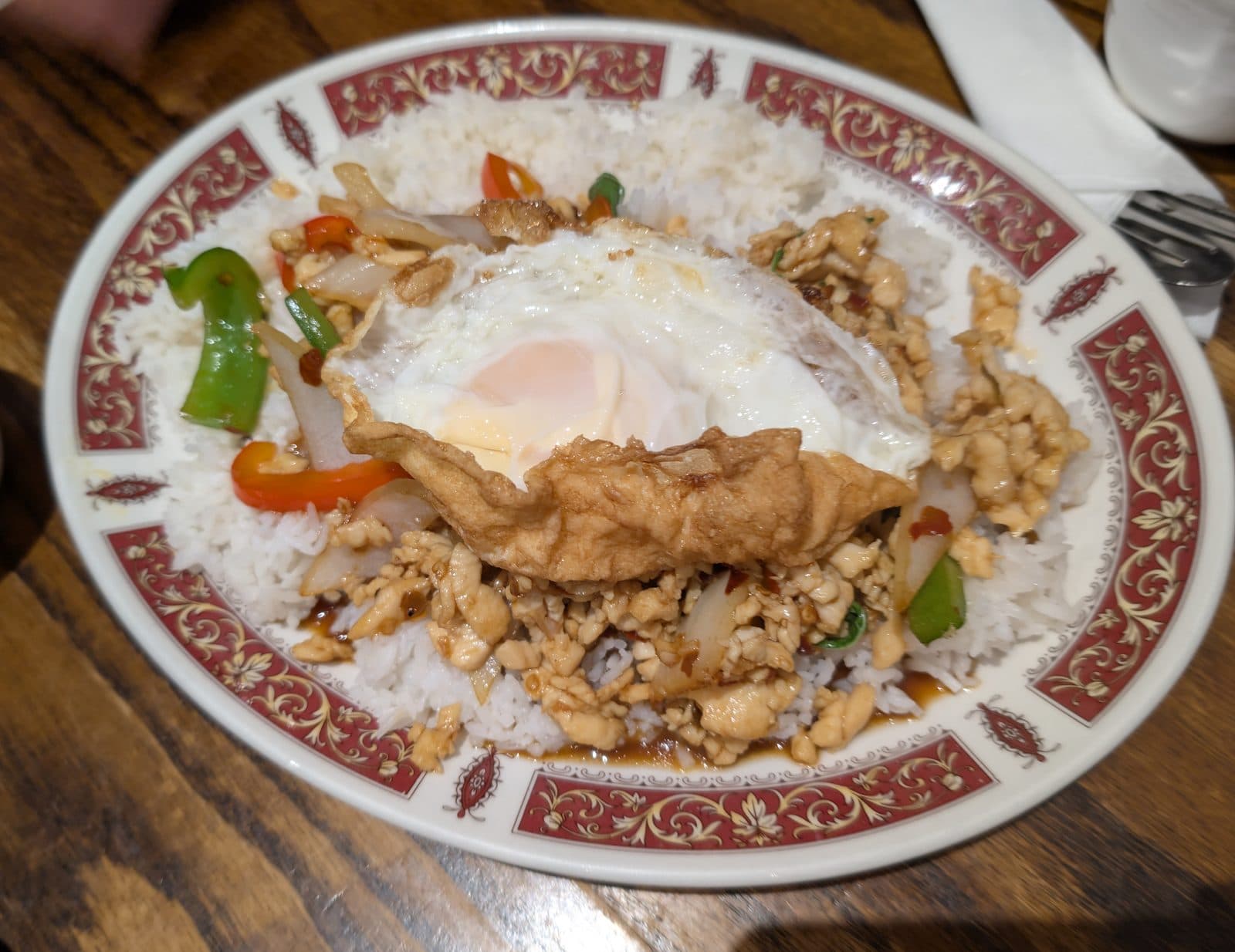 Thai basil minced chicken stir-fry with peppers and onion over rice, topped with a crispy fried egg (cropped)