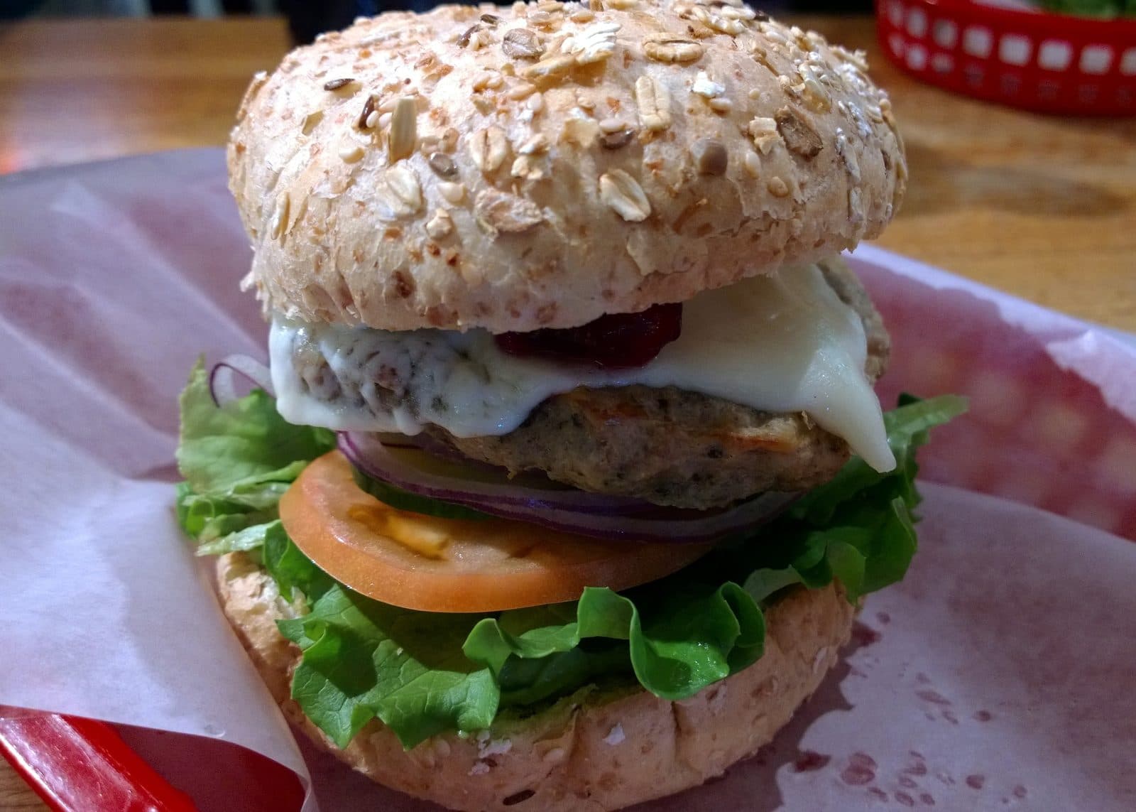 Turkey burger with melted cheese, cranberry, tomato, onion and lettuce on a multigrain bun