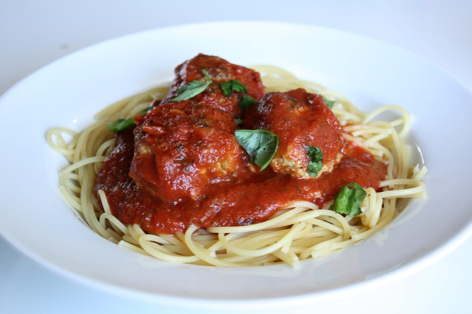 Turkey meatballs in marinara sauce over spaghetti with torn basil